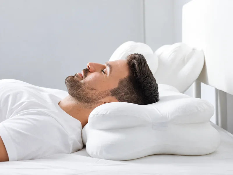 A man resting his head and neck on a contoured pillow.